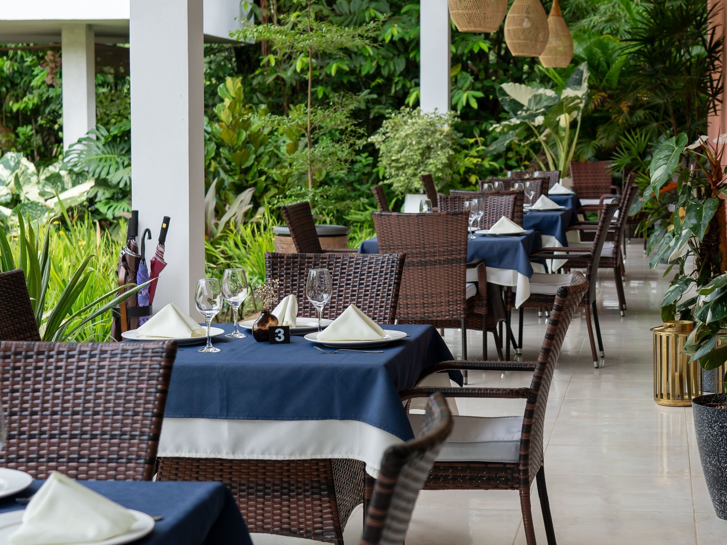 Terrace with set tables and wicker pendant lamps facing the garden at Yan's Bistro, Horquetas de Sarapiquí